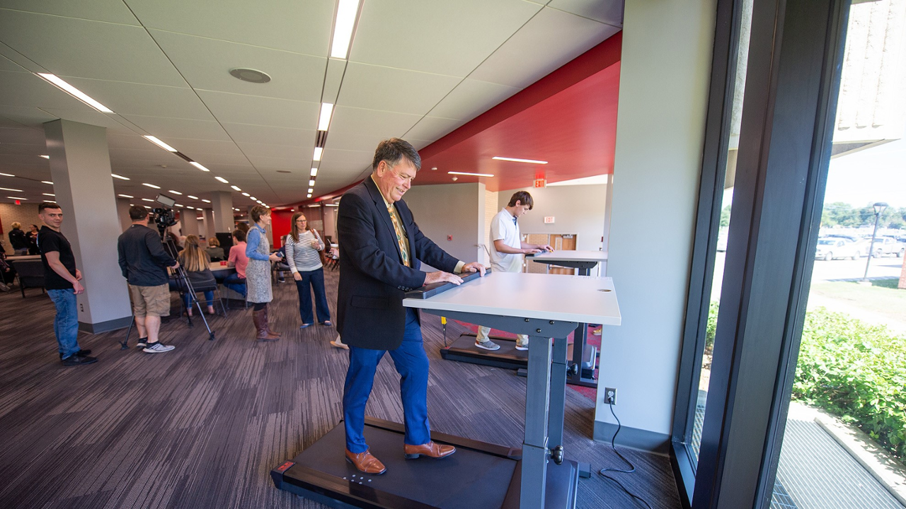 Dr. Howard Smith at a stand up desk with treadmill