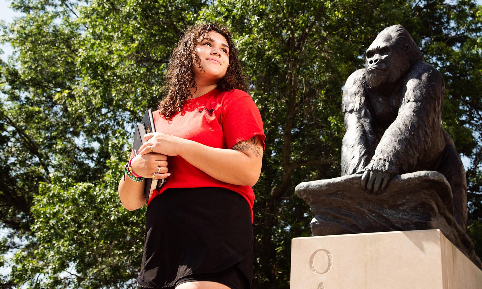 Student with books in front of gorilla statue