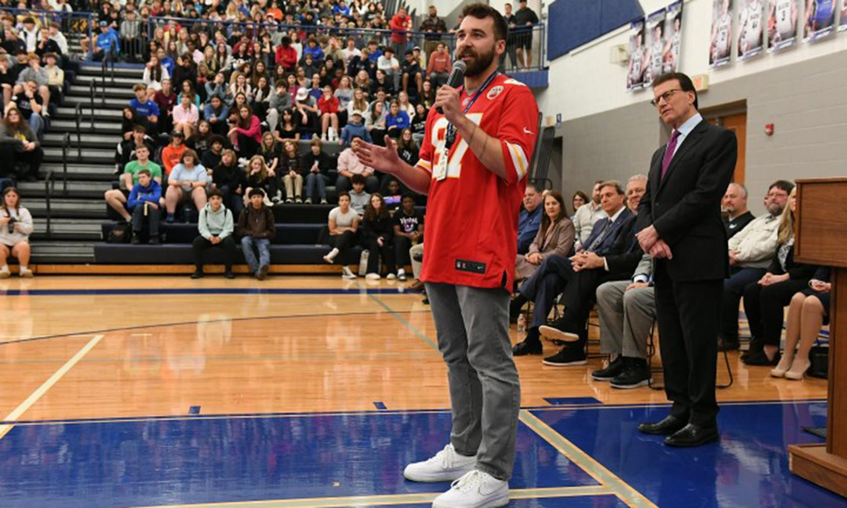 A teacher standing in a gym getting an award