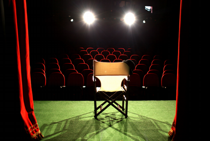 Stock photo from Canva. Photo of chair on stage with dramatic lights