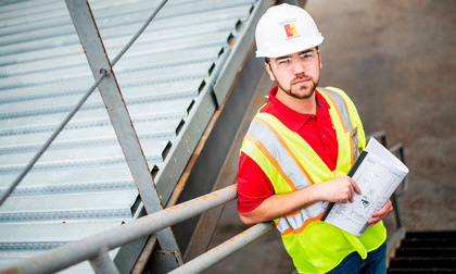 Management student in hard hat with blueprints
