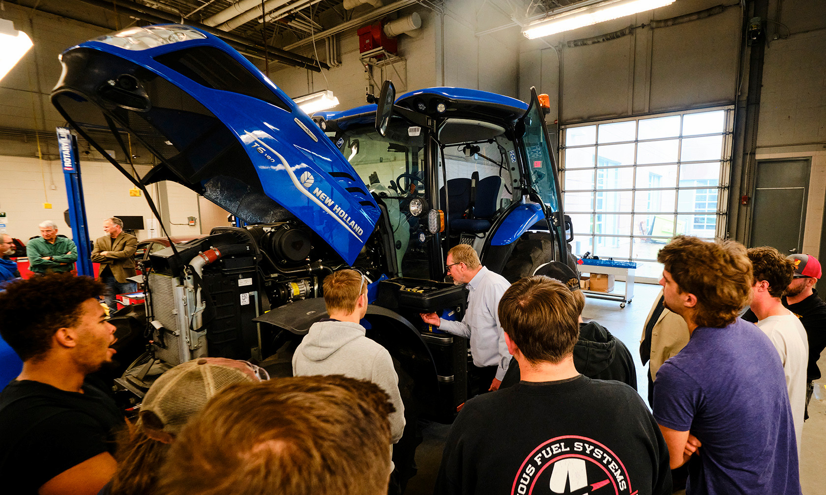 a new methane powered tractor in an automotive lab surrounded by students