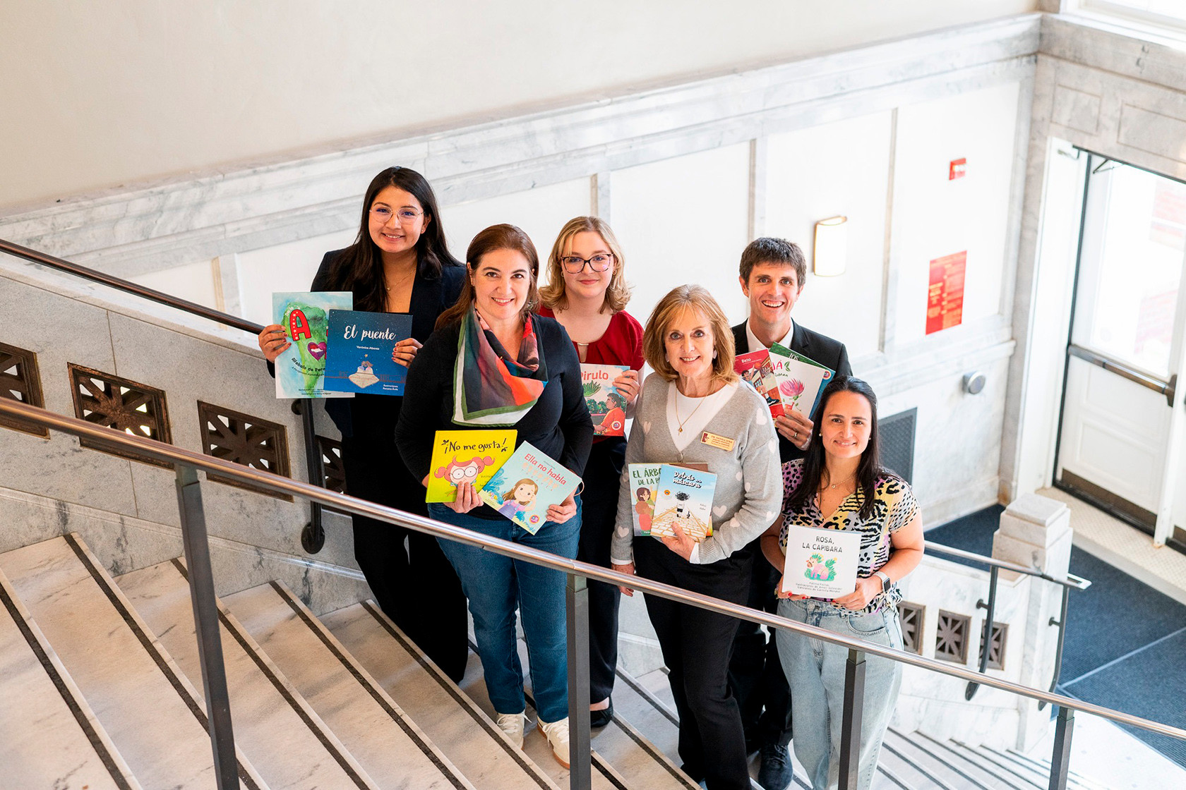 Students and faculty pose with books on the stairs of Russ hall