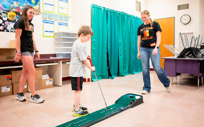 Pitt State golfers playing with student at school carnival