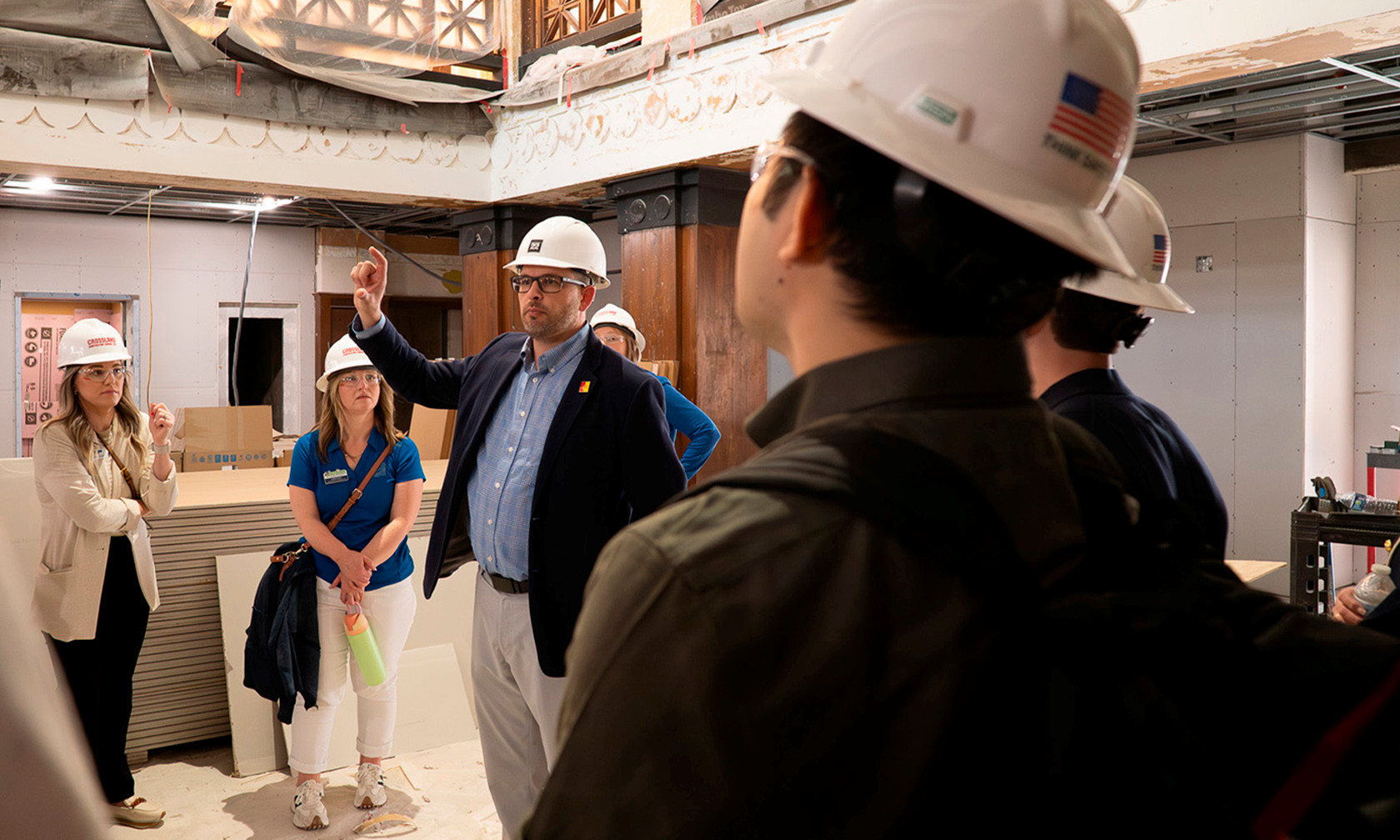 A guide in a hard hat giving a tour of Besse Hotel construction progress