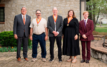 Award recipients stand with President Newsom and Charlie with their medals outside the presidential home