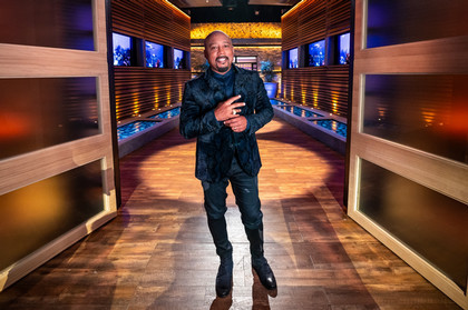 Daymond John standing on Shark Tank set smiling