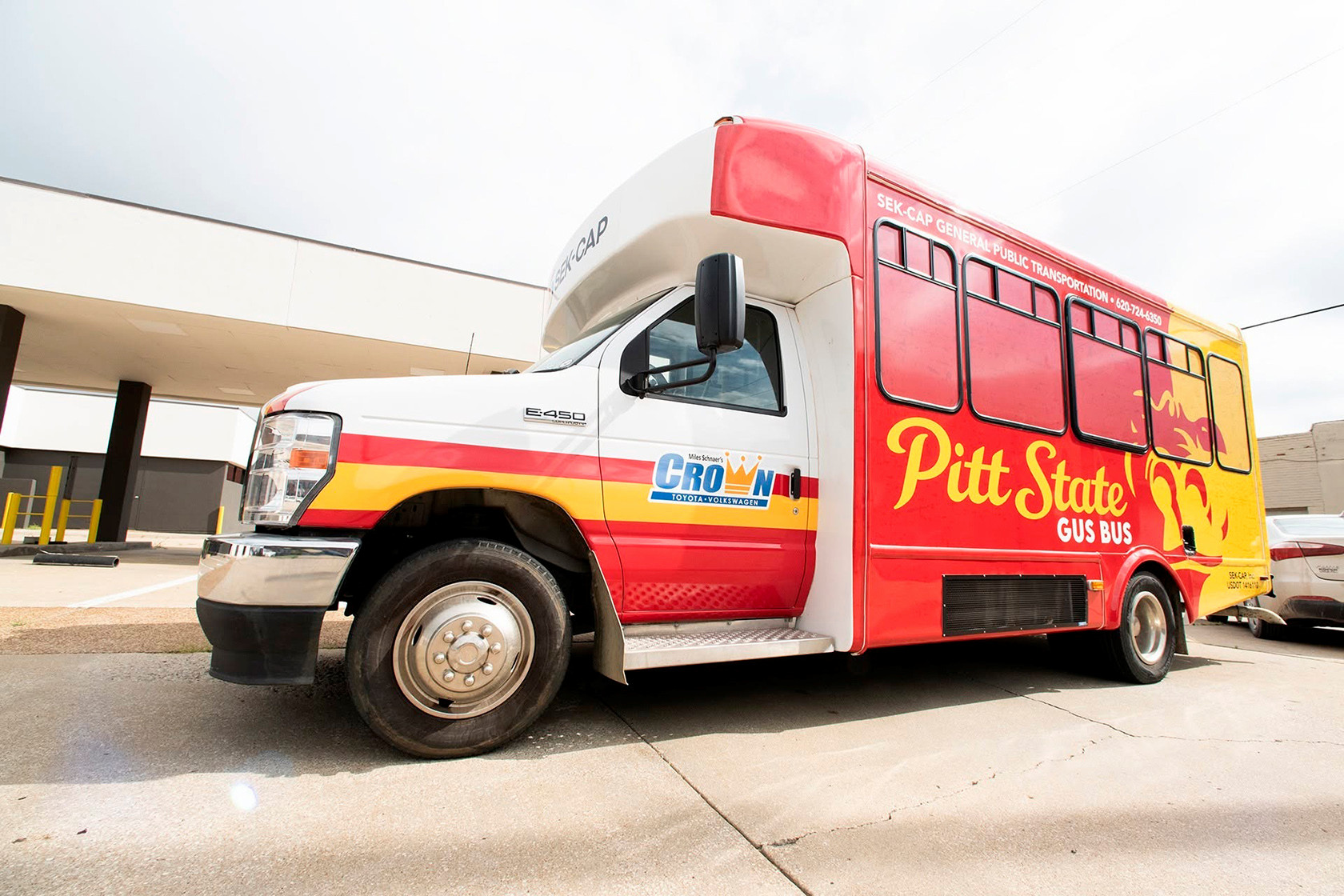 A wide angle shot of a short bus, wrapped in red and yellow with the split face