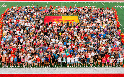 All the freshman stand on the football field taking a photo 