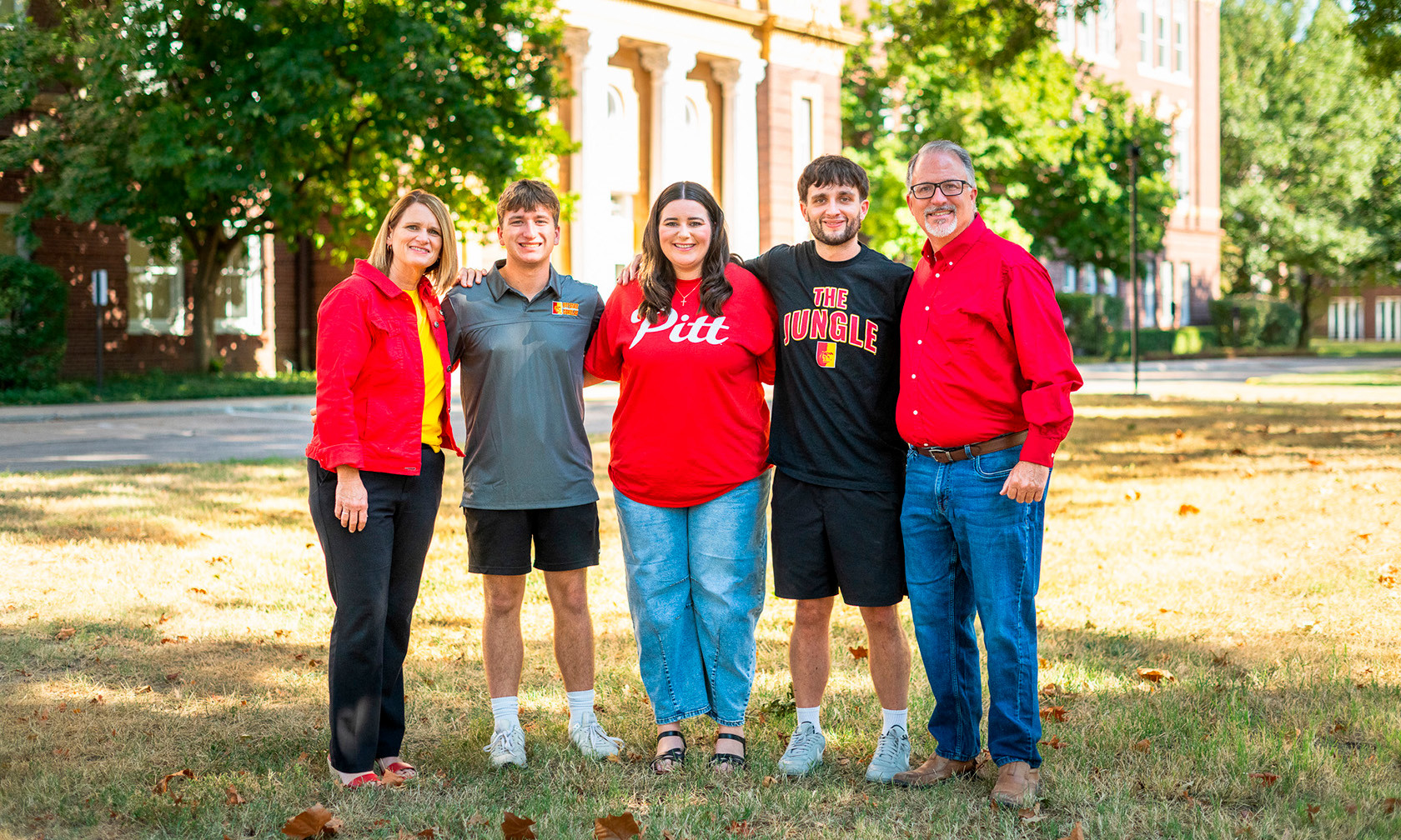 A family standing outside on a university campus, smiling