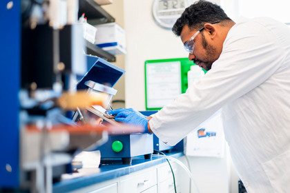 a scientist in official gear looks at a machine 