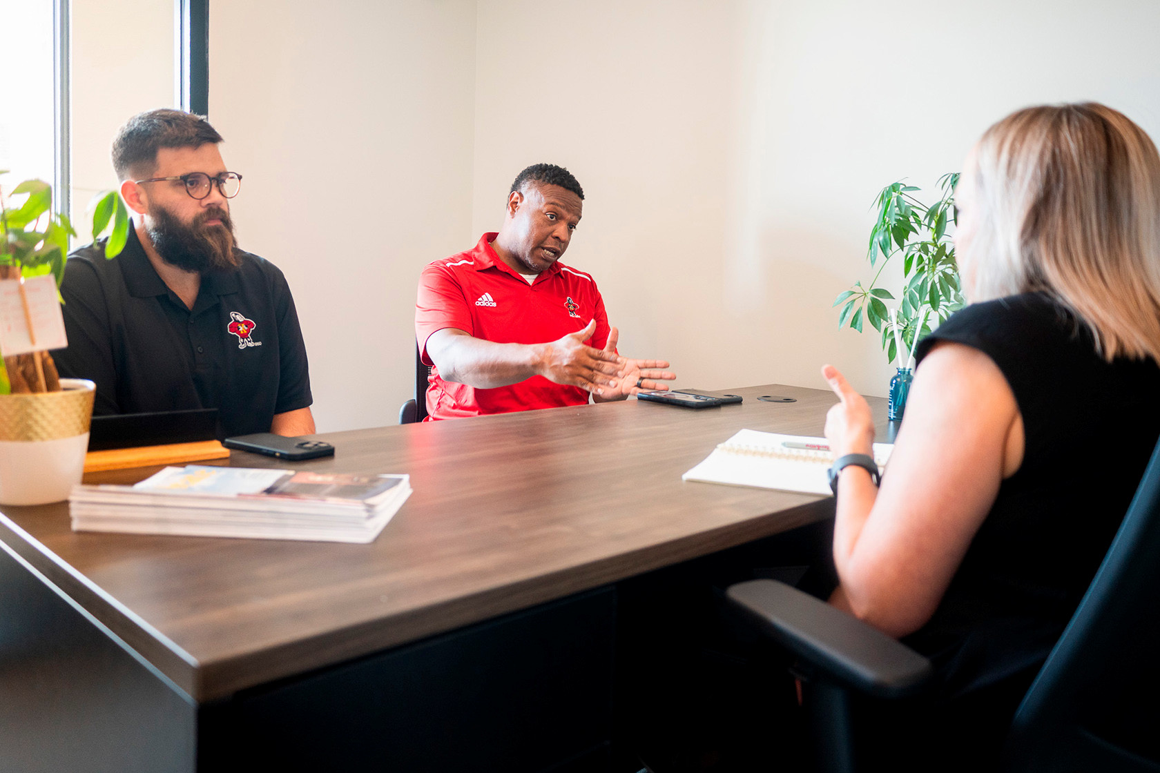 two business owners meet with advisor Amy Sawyer at her desk in a campus office.
