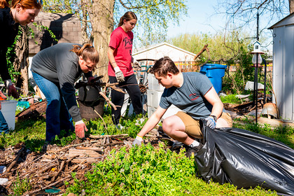 Students scoop leaves into bags outside 