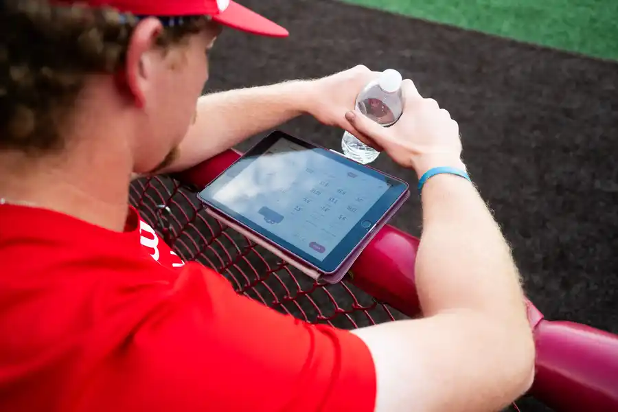 baseball player looking at ipad with statistics showing