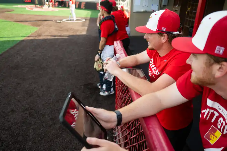 players in baseball dugout with ipad