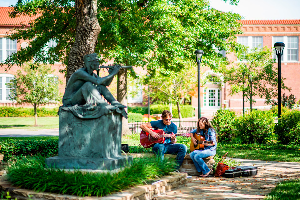 student with guitar in the summer