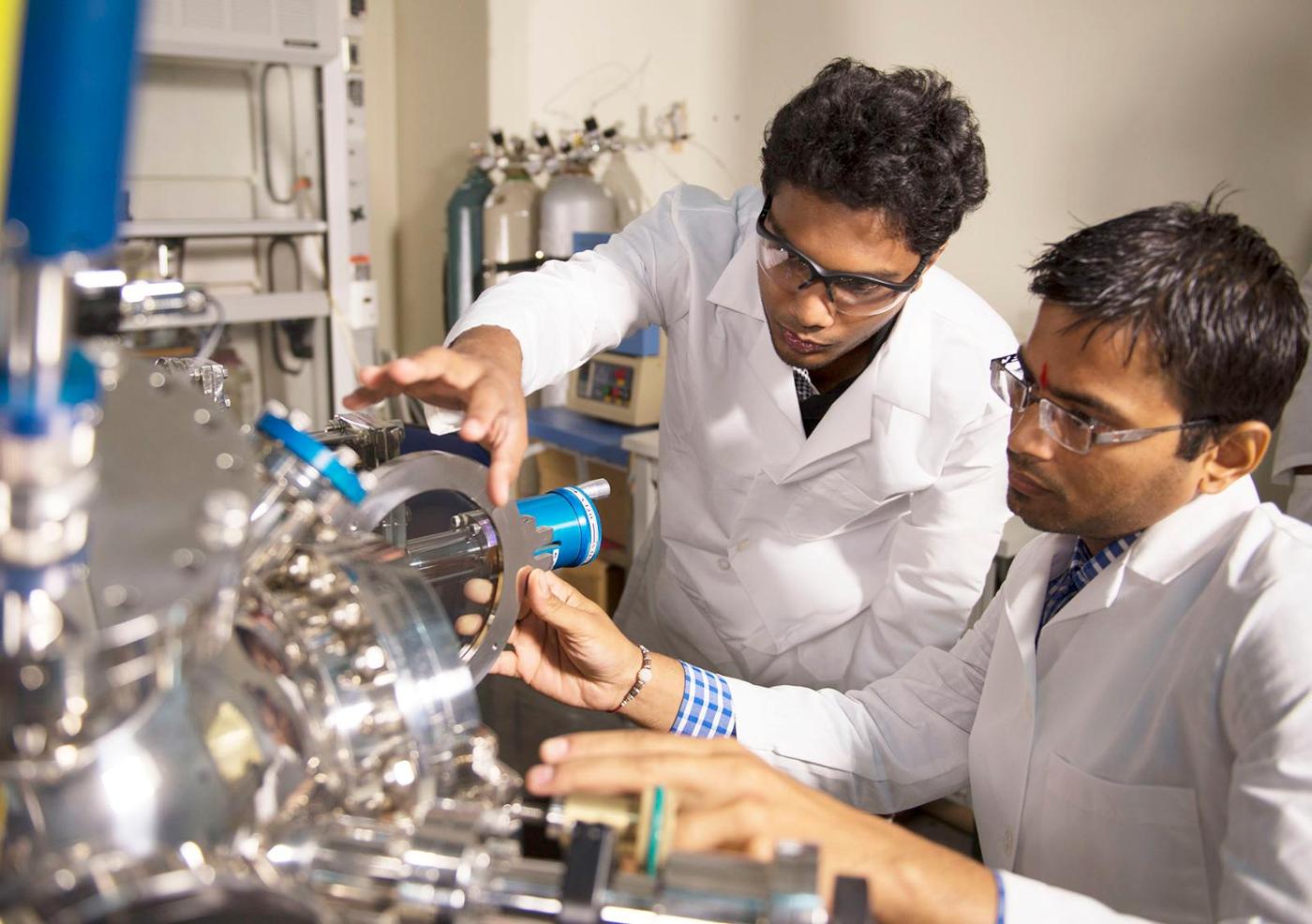 polymer chemists working with a piece of equipment